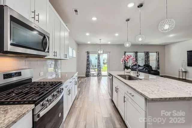 a large kitchen with stainless steel appliances granite countertop a stove and a view of microwave