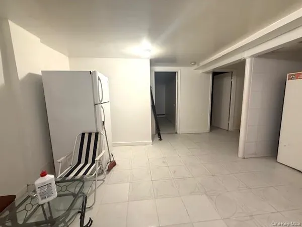 a view of a refrigerator in kitchen and an empty room