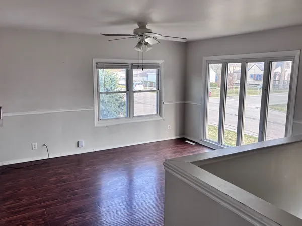 a view of an empty room with a window and wooden floor