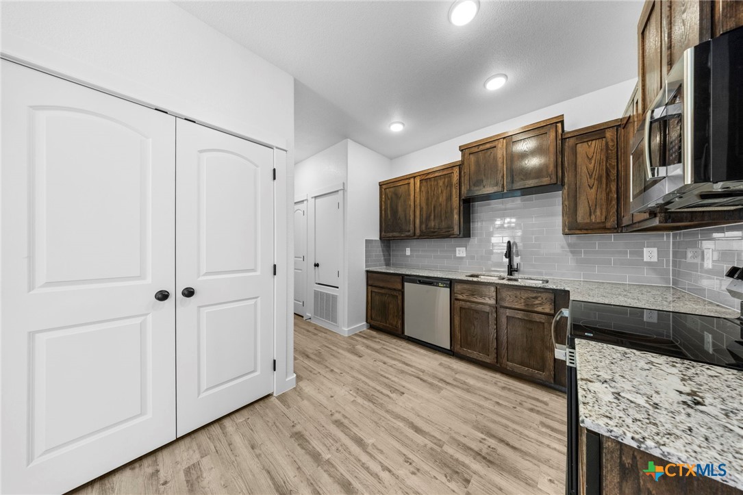 3604 Canvasback Road Killeen, TX 76542 - Photo 15 of 27 a kitchen with stainless steel appliances granite countertop a refrigerator a sink dishwasher and wooden cabinets with wooden floor