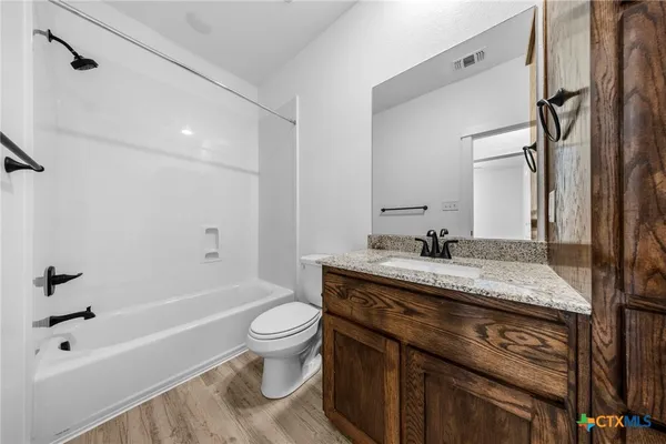 a bathroom with a granite countertop sink toilet vanity mirror bathtub and shower