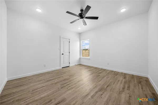 an empty room with wooden floor and ceiling fan