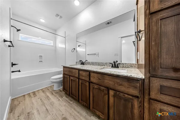 a bathroom with a granite countertop sink toilet mirror and bathtub