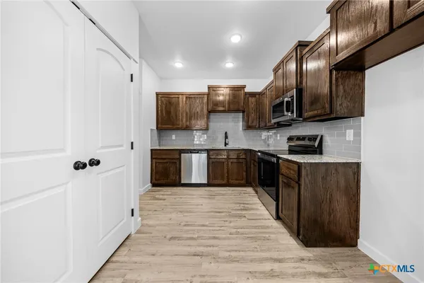 a kitchen with stainless steel appliances a refrigerator and a stove top oven