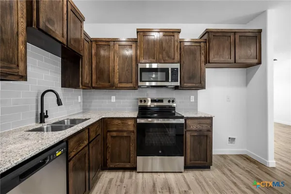 a kitchen with stainless steel appliances granite countertop a stove a sink and a microwave