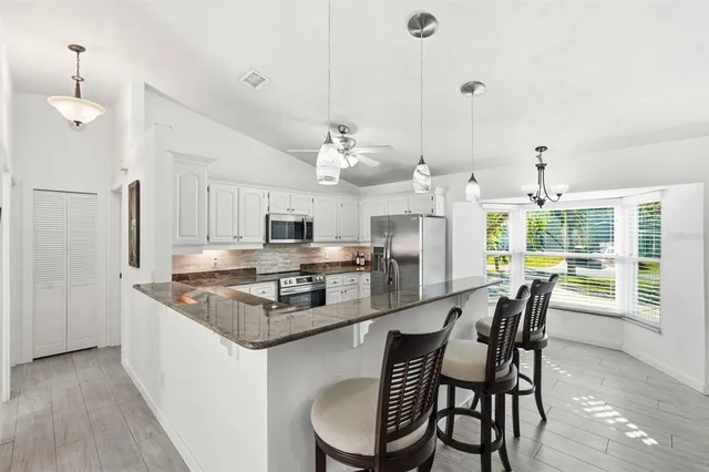 a kitchen with stainless steel appliances granite countertop a kitchen island a stove a table and chairs