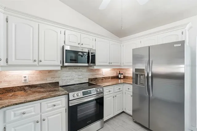 a kitchen with granite countertop white cabinets stainless steel appliances and a sink