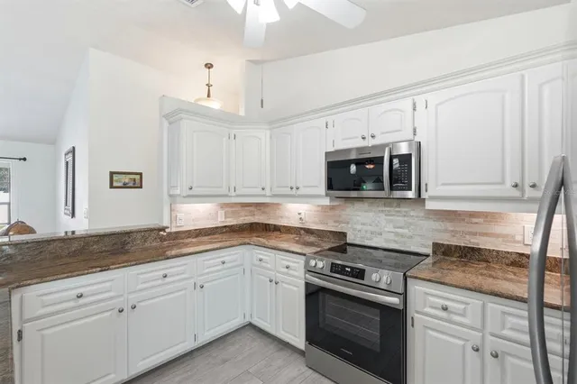 a kitchen with granite countertop white cabinets white stainless steel appliances and a sink
