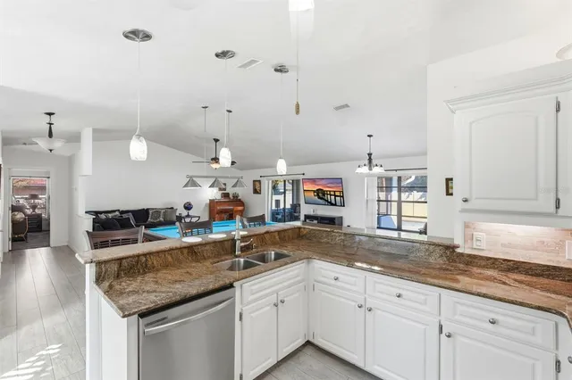 a kitchen with stainless steel appliances granite countertop a sink and a white cabinets