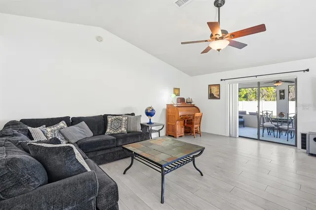 a living room with furniture a ceiling fan and a wooden floor