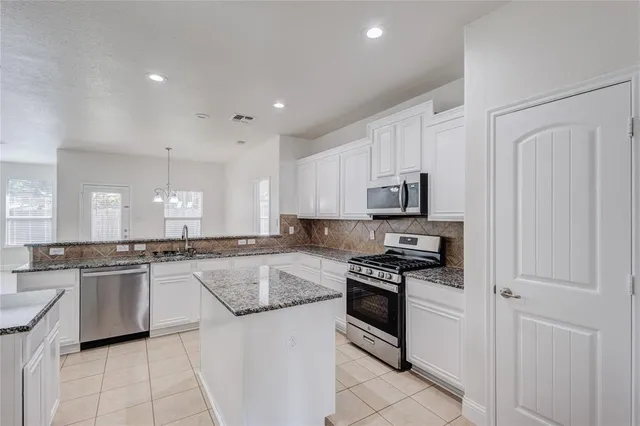 a kitchen with stainless steel appliances granite countertop a stove top oven a sink dishwasher and a refrigerator