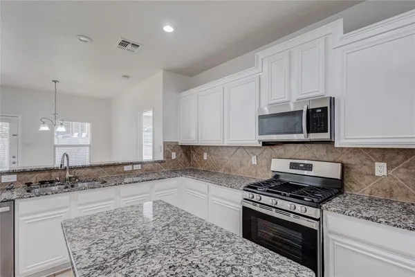 a kitchen with stainless steel appliances granite countertop a stove a sink and a microwave