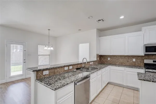 a kitchen with granite countertop a sink and white cabinets