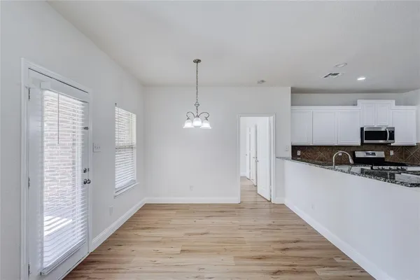 a kitchen with stainless steel appliances granite countertop a refrigerator a sink dishwasher a stove and white countertops with wooden floor