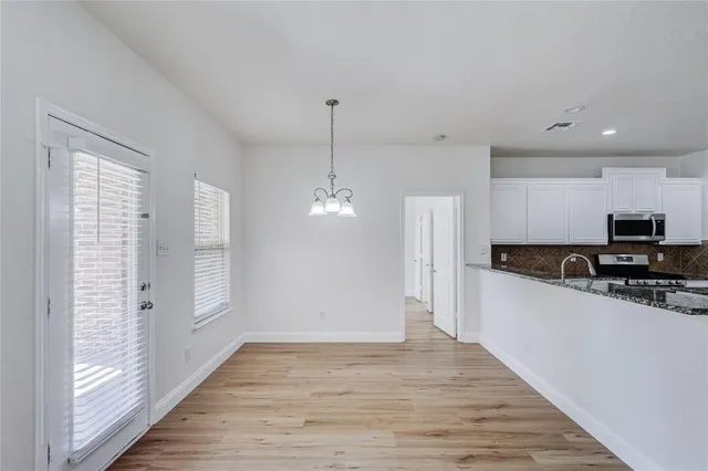 a kitchen with stainless steel appliances granite countertop a refrigerator a sink dishwasher a stove and white countertops with wooden floor