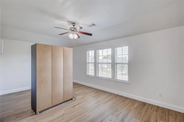 a view of an empty room with a window and wooden floor