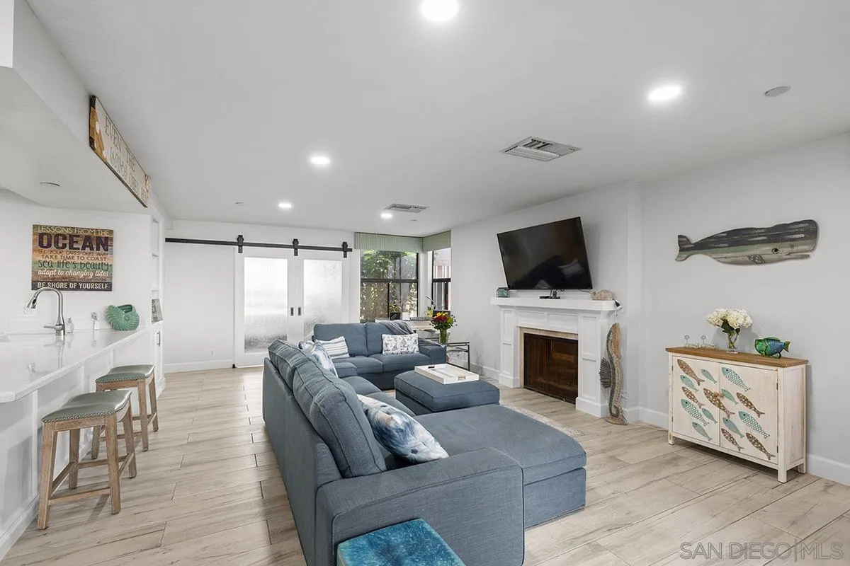 1125 Pacific Beach Drive, Unit 104 San Diego, CA 92109 - Photo 16 of 67 a living room with furniture a flat screen tv and a fireplace