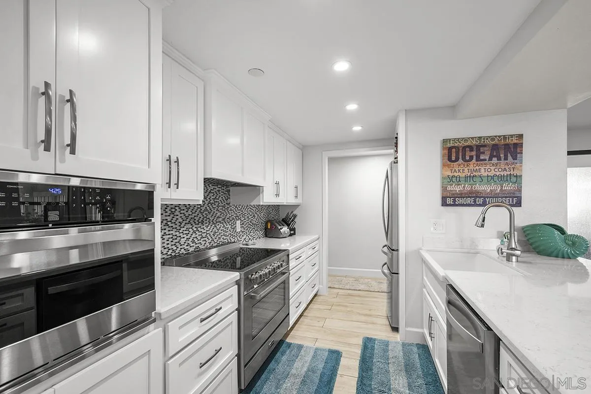1125 Pacific Beach Drive, Unit 104 San Diego, CA 92109 - Photo 5 of 67 a large kitchen with stainless steel appliances granite countertop a stove a sink and a refrigerator