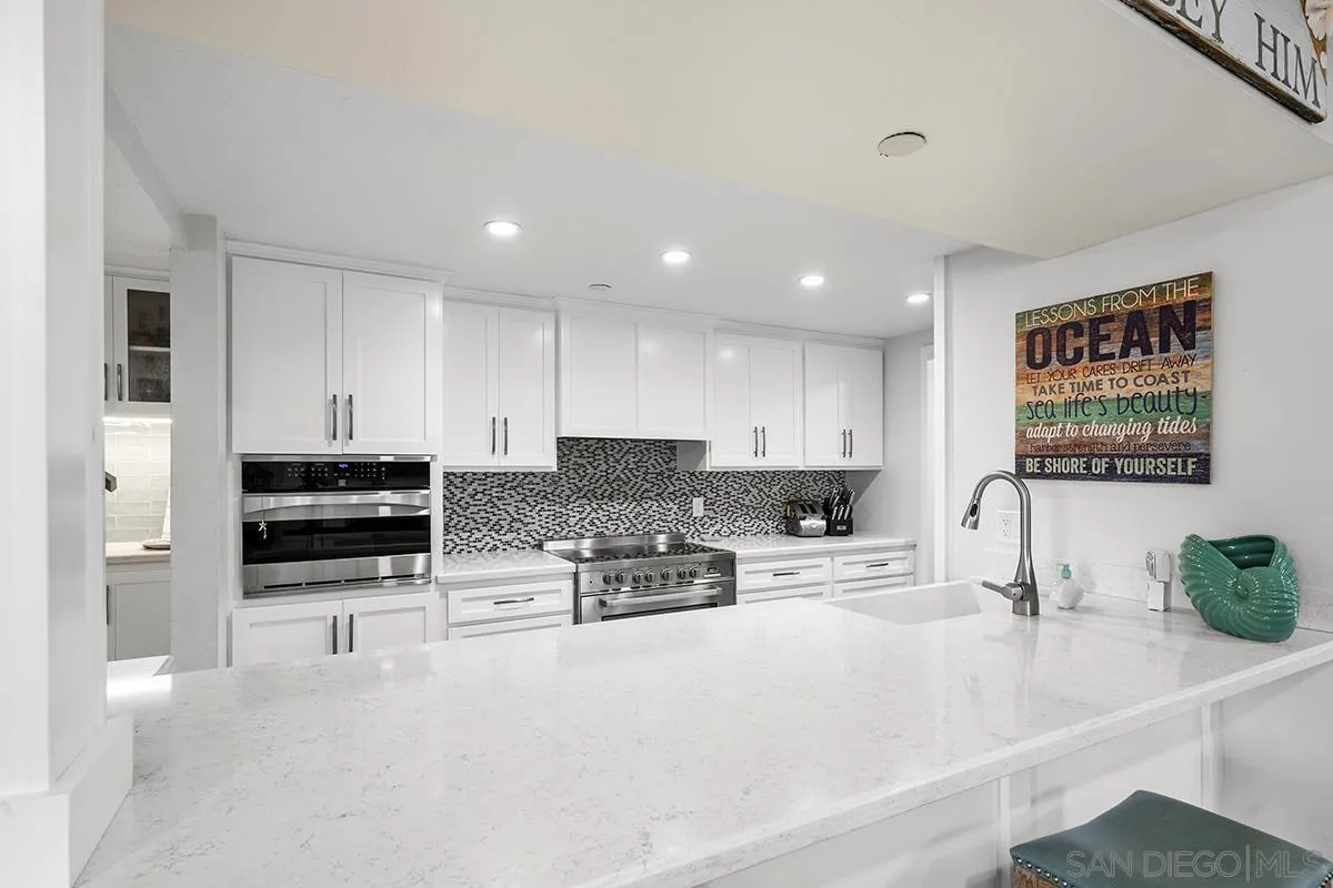 1125 Pacific Beach Drive, Unit 104 San Diego, CA 92109 - Photo 6 of 67 a kitchen with stainless steel appliances a stove a sink a microwave and cabinets