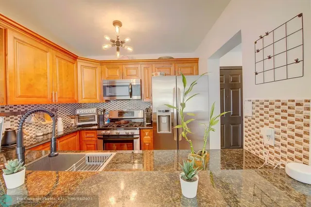 a kitchen with granite countertop a stove a sink and a refrigerator