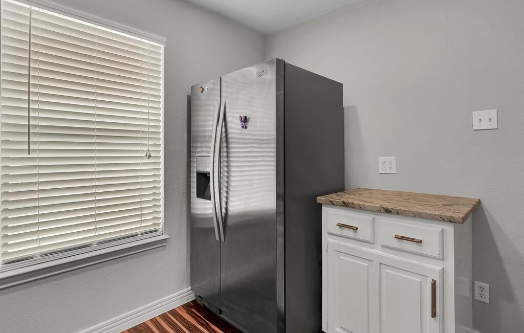 1362 South 12th Street, Unit 22 Waco, TX 76706 - Photo 13 of 31 Stainless steel side-by-side refrigerator, white cabinetry with bronze hardware, and wood-finish flooring