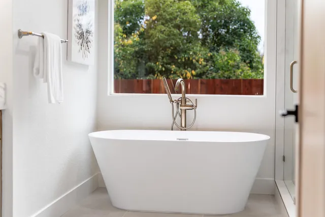 a white bath tub sitting in a bathroom next to a window