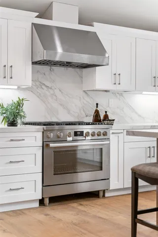 a kitchen with stainless steel appliances a refrigerator a stove a sink a dining table and chairs