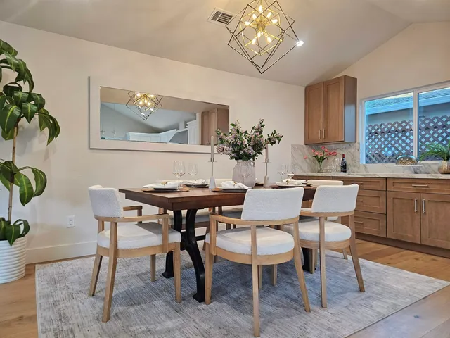 a dining room with furniture a rug and a potted plant