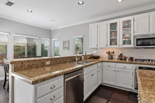 a kitchen with granite countertop a sink and white cabinets