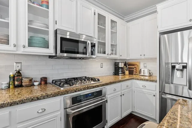 a kitchen with granite countertop white cabinets and stainless steel appliances