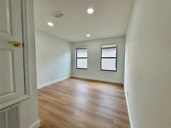an empty room with wooden floor and windows