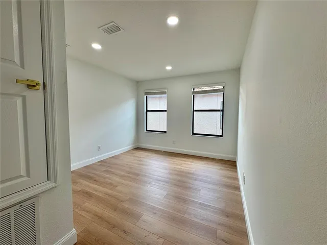 an empty room with wooden floor and windows