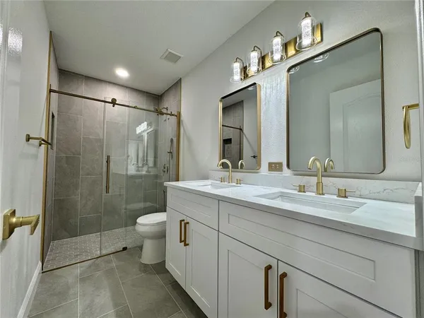 a bathroom with a double vanity sink toilet and shower