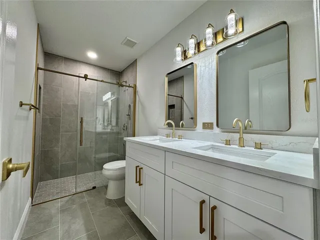 a bathroom with a double vanity sink toilet and shower
