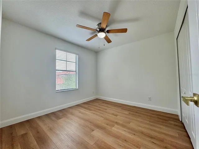 an empty room with wooden floor fan and windows