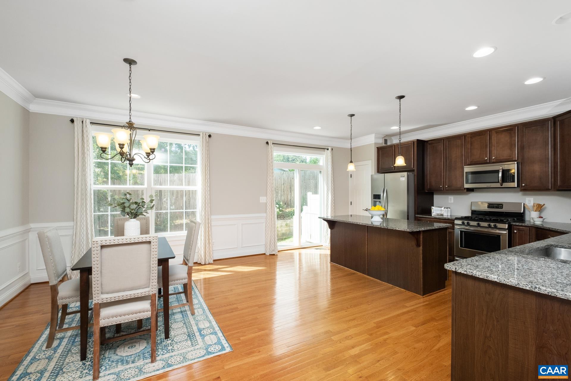 2104 Avinity Loop Charlottesville, VA 22902 - Photo 14 of 45 a large open kitchen with a refrigerator a stove top oven and a dining table with wooden floor