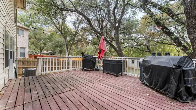 a view of a deck with wooden floor and fence with a large tree