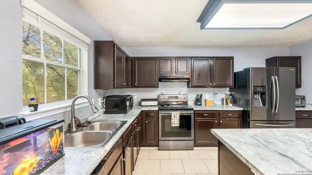 a kitchen with kitchen island granite countertop a sink stove refrigerator and cabinets