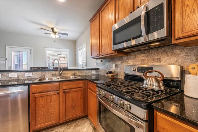 a kitchen with granite countertop stainless steel appliances a sink cabinets and a stove top oven