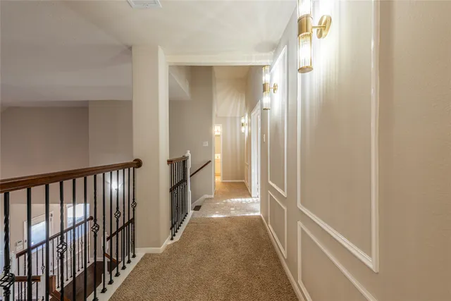 a view of a hallway with wooden floor and a bathroom