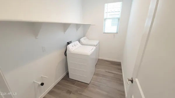 a view of an empty room with wooden floor and a kitchen