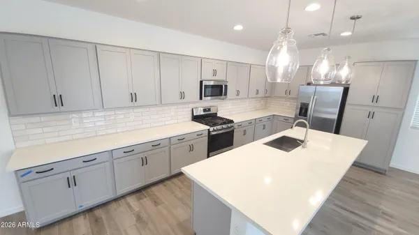 a kitchen with a sink dishwasher a stove a refrigerator and cabinets with wooden floor