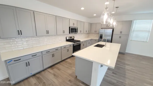 a kitchen with a sink a stove a refrigerator and white cabinets