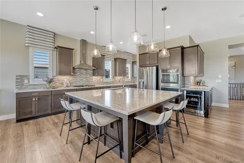 a kitchen with stainless steel appliances a dining table chairs and wooden floor