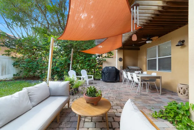 a view of a patio with couches table and chairs under an umbrella with a barbeque