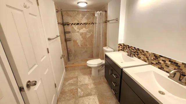 a spacious bathroom with a sink a toilet a mirror a shower and vanity