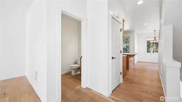 a view of a hallway with wooden floor and a bathroom