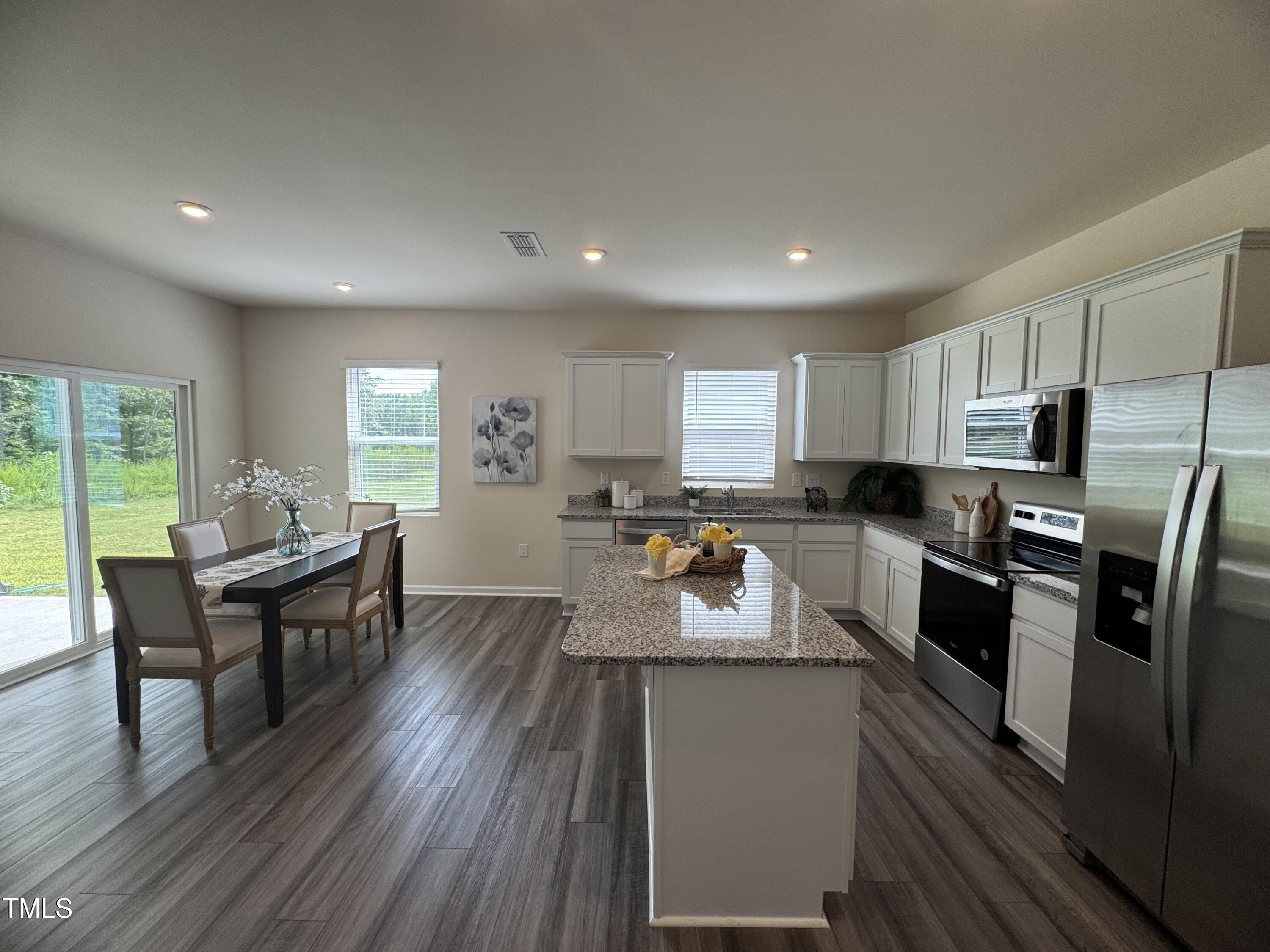 1444 Heron Pond Street Raleigh, NC 27604 - Photo 32 of 37 a kitchen with a refrigerator a stove top oven a sink dishwasher and white cabinets with wooden floor