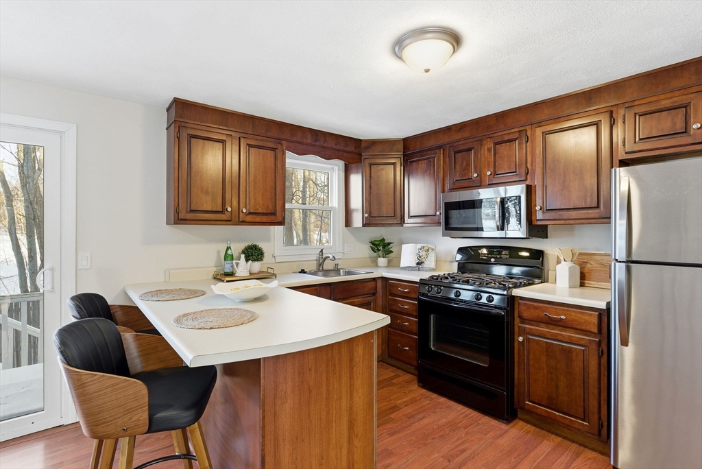 80 Swan Street, Unit 223 Lowell, MA 01852 - Photo 3 of 20 a kitchen with stainless steel appliances granite countertop a stove a sink dishwasher a stove a refrigerator with a dining table and chairs