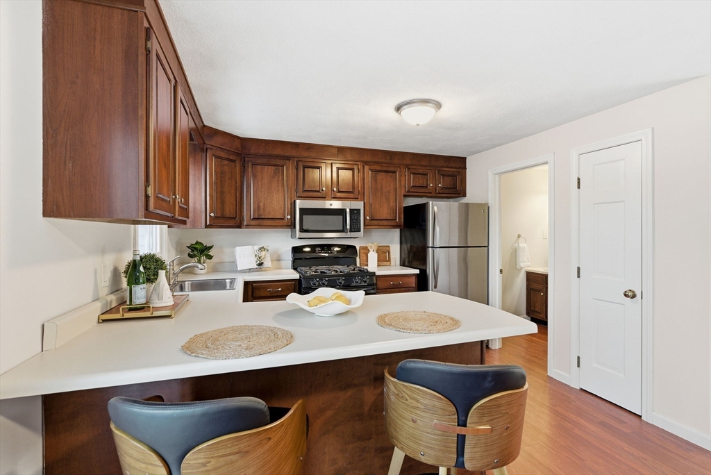 80 Swan Street, Unit 223 Lowell, MA 01852 - Photo 6 of 20 a kitchen with stainless steel appliances a refrigerator a sink a stove a dining table and chairs